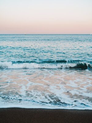 Gentle ocean waves wash ashore on a sandy beach.